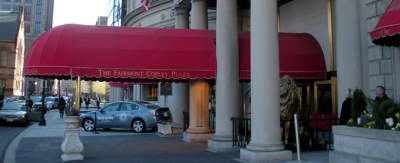 The entrance of a hotel with an awning over a vehicle.